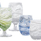 Six glasses from the Juliska Puro Marbled Drinkware Collection feature seaglass hues in blue, green, and gray swirled patterns—both stemmed and stemless—arranged in two rows, each resembling a marbled goblet.
