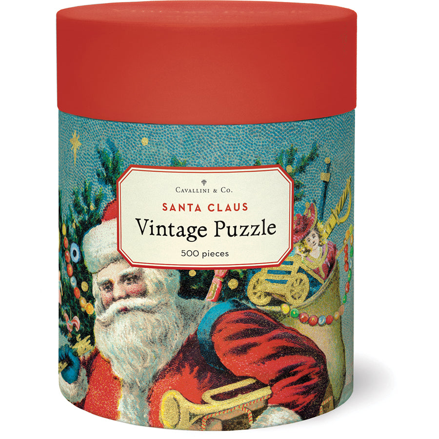 Cavallini Papers and Co’s Santa Claus 500 Piece Puzzle comes in a cylindrical box with a red lid, featuring vintage Santa imagery from the Cavallini archives.