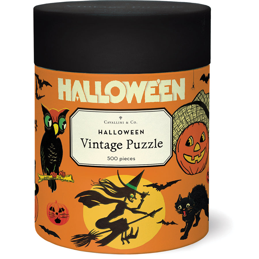 The Halloween Vintage 500 Piece Puzzle by Cavallini Papers and Co features vintage witches, black cats, owls, bats, and jack-o’-lanterns on a festive orange background in a round container.