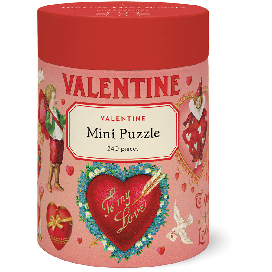 A cylindrical red and pink Cavallini Papers and Co box labeled "Valentine Mini Puzzle, 240 pieces" features vintage Valentine’s Day art and heart motifs.