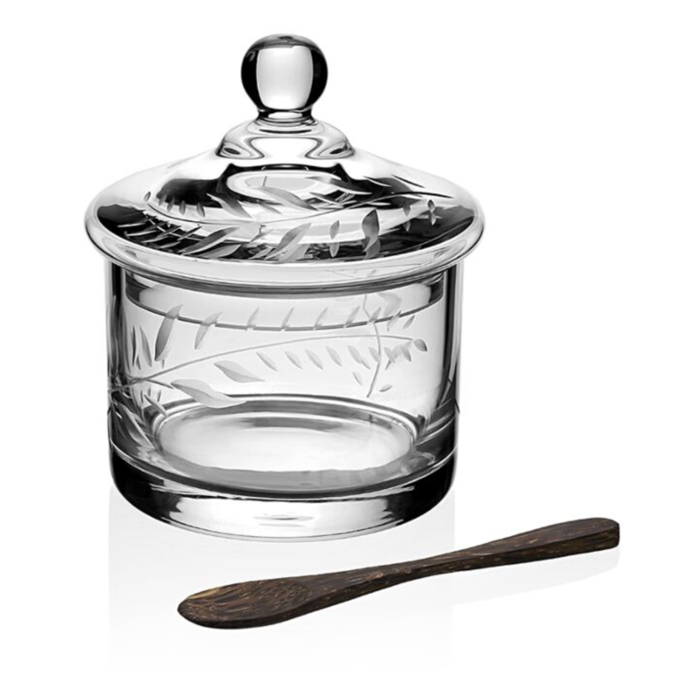The Jasmine Covered Honey Jar with Spoon by William Yeoward Crystal features a clear glass jar with an engraved lid and comes with a small palm wood spoon, all displayed against a white background.