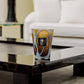 Artistic glass tumbler on a sleek black coffee table accompanied by a Baobab Collection Stones Agate Candle in a modern living room setting.