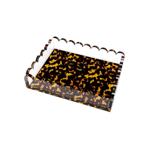 The Tortoise Scallop Tray by Tara Wilson Designs features scalloped edges and a stylish tortoiseshell pattern in brown, yellow, and black—a chic accent for any room.