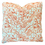 The Cowrie Shell Coral Outdoor Pillow by Associated Design features a peach background with a white and orange leaf pattern, expertly crafted from premium materials for lasting comfort and style.