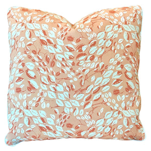 The Cowrie Shell Coral Outdoor Pillow by Associated Design features a peach background with a white and orange leaf pattern, expertly crafted from premium materials for lasting comfort and style.