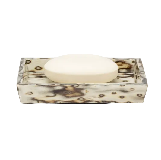 A round bar of white soap rests in a rectangular Bisbee Bath Collection soap dish featuring a marbled cream and brown birdseye burl veneer pattern.