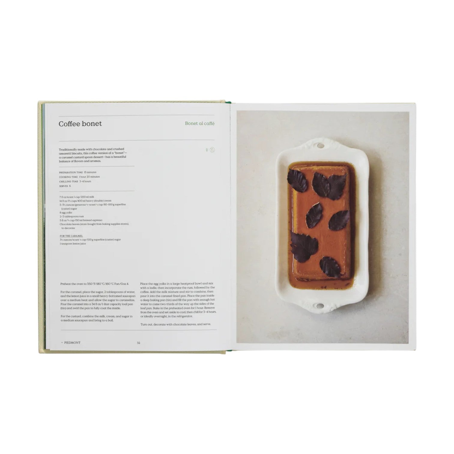 An open copy of The Regional Italian Cookbook by Phaidon shows a coffee bonet recipe on the left and a rectangular chocolate dessert with chocolate leaves on a white platter on the right.