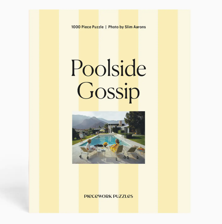 The “Slim Aarons Puzzle Collection” by Piecework is a 1000-piece jigsaw puzzle featuring a photo of people sitting by a pool with mountains and a modern house in the background, printed on high-quality art paper for vibrant colors and durability.