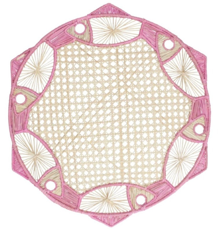 The Fish Meeting Raffia Placemat by Mercedes Salazar features a beige center with a pink and white geometric border with circular and fan patterns, perfect as an exclusive handcrafted accent for your table setting.
