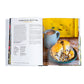 The open Red Truck Bakery Cookbook by Penguin Random House displays a farmhouse muffins recipe on the left page and a photo of muffins alongside a mug of coffee on the right, all set against a cheerful yellow background—evoking the cookbook’s signature warmth and charm.