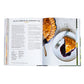 An open copy of the Red Truck Bakery Cookbook from Penguin Random House displays a recipe for Blue Ribbon Blueberry Pie on the left page and a photo of the pie with a slice revealing blueberry filling on a white plate on the right—evoking classic southern baking traditions.