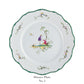 The Raynaud Longjiang Dinnerware Collection dinner plate features a scalloped green-trimmed edge, floral rim accents, and a central illustration of two people by a tree in a classic pastoral scene. Text below reads "Dinner Plate No. 5".