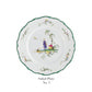 The Raynaud Longjiang Dinnerware Collection Salad Plate No. 3 features a white base with scalloped green-trimmed edge, a painted pastoral scene of two figures by a tree, and floral accents, inspired by Vieux Marseille faience.