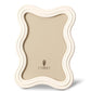 Part of the L'Objet White Ripple Enamel Frame Collection, this cream-colored picture frame features a wavy edge, an off-white enamel finish, a beige inner background, and the L'Objet logo at the bottom center.