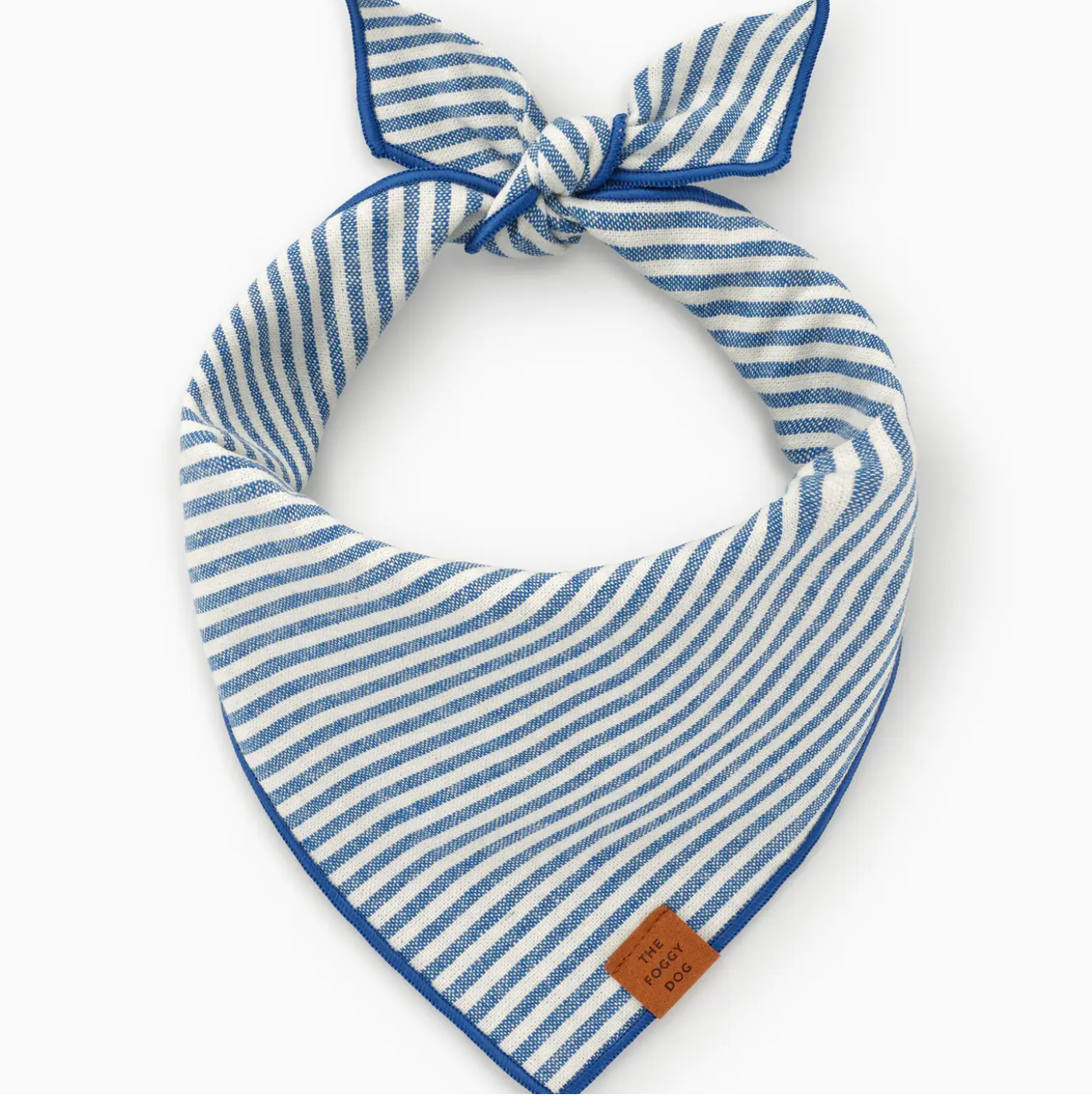 The Lake Blue Stripe Dog Bandana by Foggy Dog features blue and white stripes, a small brown tag, and an adjustable design for a comfy fit. Knotted at the top, it's displayed on a white background.