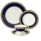 The Ashbourne Navy Dinnerware Collection by Royal Crown Derby is a four-piece fine bone china set with dark blue and gold trim, featuring a dinner plate, salad plate, teacup, and saucer on a classic white background.