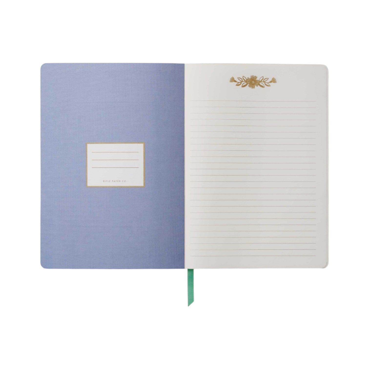 The Aster Softcover Journal by Rifle Paper Co. features a light blue inside cover with a label, lined cream pages adorned with a gold floral design at the top, and a green ribbon bookmark.