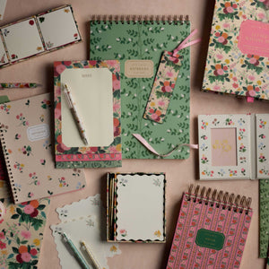 The Rifle Paper Co. Climbing Vines Large Top Spiral Notebook, featuring a floral design and ruled pages, is showcased alongside coordinating notepads and bookmarks on a light surface.