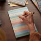 Using the Rifle Paper Co. Muted Numbered Color Block Memo Notepad, someone lists tasks—like walking the dog, grocery shopping, and reading—on tear-off sheets for easy daily organization.