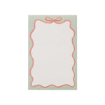 The Rifle Paper Co. Ribbon Notepad features a blank notecard with a scalloped pink border, bow design, and mint accents on a light green background.