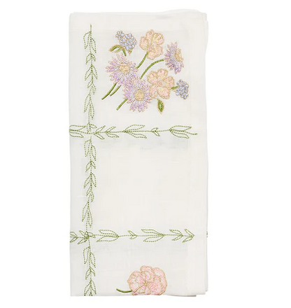 The Kim Seybert Trellis Napkin Set features folded white napkins embroidered with pink and purple flowers and green vines—perfect spring table accents or charming Easter napkins.
