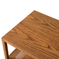 Close-up view of the Orca Side Table by Julian Chichester, highlighting its rectangular African Walnut design with a visible wood grain pattern and an undershelf featuring an antiqued rattan surface.