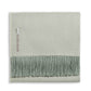 Alicia Adams Alpaca’s Classic Herringbone Throw Collection features a folded light green baby alpaca blanket with fringed edges and a fabric label, fair-trade made in Peru for luxurious softness.