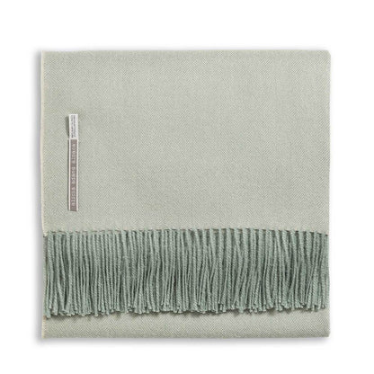Alicia Adams Alpaca’s Classic Herringbone Throw Collection features a folded light green baby alpaca blanket with fringed edges and a fabric label, fair-trade made in Peru for luxurious softness.