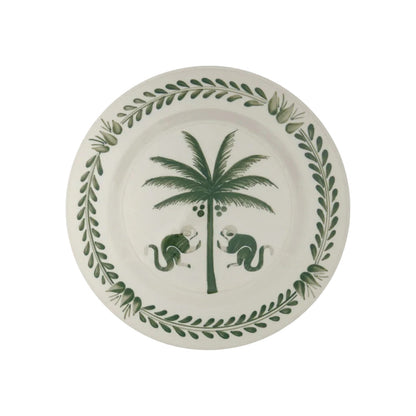 From the Casa Dark Jungle Dinnerware Collection by Johanna Ortiz, this white ceramic plate showcases a hand-painted green palm tree with two monkeys and a leafy border, inspired by Carmen de Viboral’s artisanal heritage.