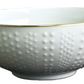 Inspired by French artisans, the Corail Gold Collection by Medard de Noblat/Devine features a white ceramic bowl with a textured dotted exterior and a delicate gold rim.