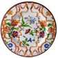 The Pancale White Melamine Dinnerware Collection by Mario Luca Giusti features a vibrant floral and vine motif in orange, green, blue, and red on a white background.