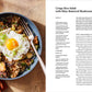 A bowl of rice salad topped with sautéed mushrooms, chopped greens, sunflower seeds, and a sunny-side-up egg sits beside a copy of Salad Seasons by Rizzoli—an inspiring scene for anyone seeking healthy salads or flipping through this beloved cookbook for new vegetable recipes.