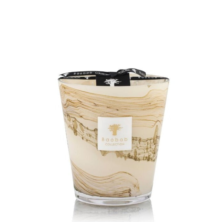 A Baobab Sand Siloli candle in a decorative swirled hand-blown glass holder with a branded label, isolated on a white background.