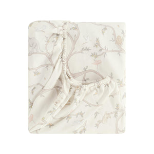 The Gooselings Animal Parade Ivory Bedding Collection features a folded fitted crib sheet in pale beige with a subtle pattern of tree branches, birds, and animals—perfect for cozy children’s bedding and sweet dreams.