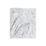 The Gooselings Animal Parade Blue Bedding is a folded fitted sheet with safari animals and tree branches in neutral tones on a light background, made from breathable, pure materials and OEKO-TEX certified for safe and comfortable baby bedding.