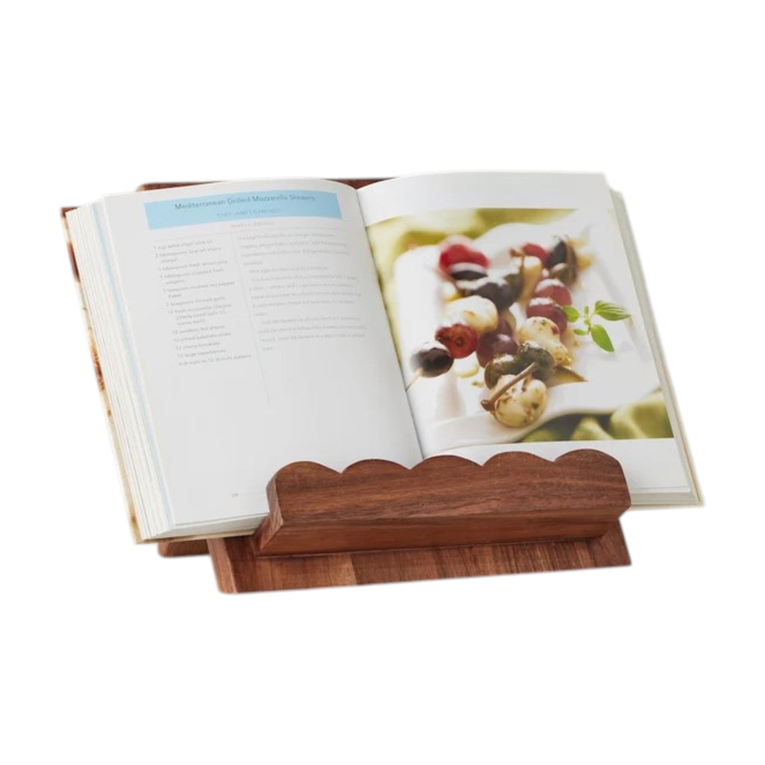 An open cookbook rests on the etúHOME Scalloped Wood Book Stand, crafted from acacia wood, displaying a recipe page and a photo of skewered appetizers.