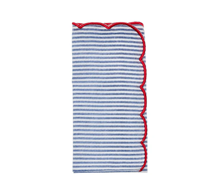 The Kim Seybert Fiesta Napkin Set features folded seersucker napkins with horizontal blue and white stripes and wavy red trim along the scalloped edge.