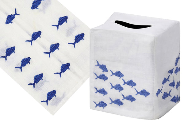 Two images of a hand embroidered tissue box cover from the Haute Home School of Fish Collection, Blue; one close-up showing Italian linen fabric with blue fish patterns and the other depicting the cover on a square tissue box.