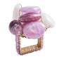 The Kim Seybert Sea Stone Napkin Ring features a gold wire design with a square base, accented by pink and purple polished beads and beach stones for an elegant coastal style.