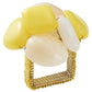 The Kim Seybert Sea Stone Napkin Ring features a gold square base adorned with large, smooth yellow and white stones clustered on top, evoking the look of beach pebbles.