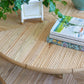 The Sea Cliff Coffee Table by Selamat, measuring 46"W x 18.7"D x 34"H, features two stacked books and a green ivy plant in a white planter on top. A small turquoise vase is also placed on the table for a pop of color.