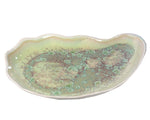 AE Ceramics' Large Oyster Plate Collection features a ceramic dish with scalloped edges and a green and brown speckled glaze, ideal for use as a dessert bowl.