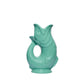The Original Gluggle Jug's Fish Gluggle Jug Collection features ceramic jugs shaped like fish with glossy turquoise glaze, open mouth spout, and loop handle—an iconic British design.