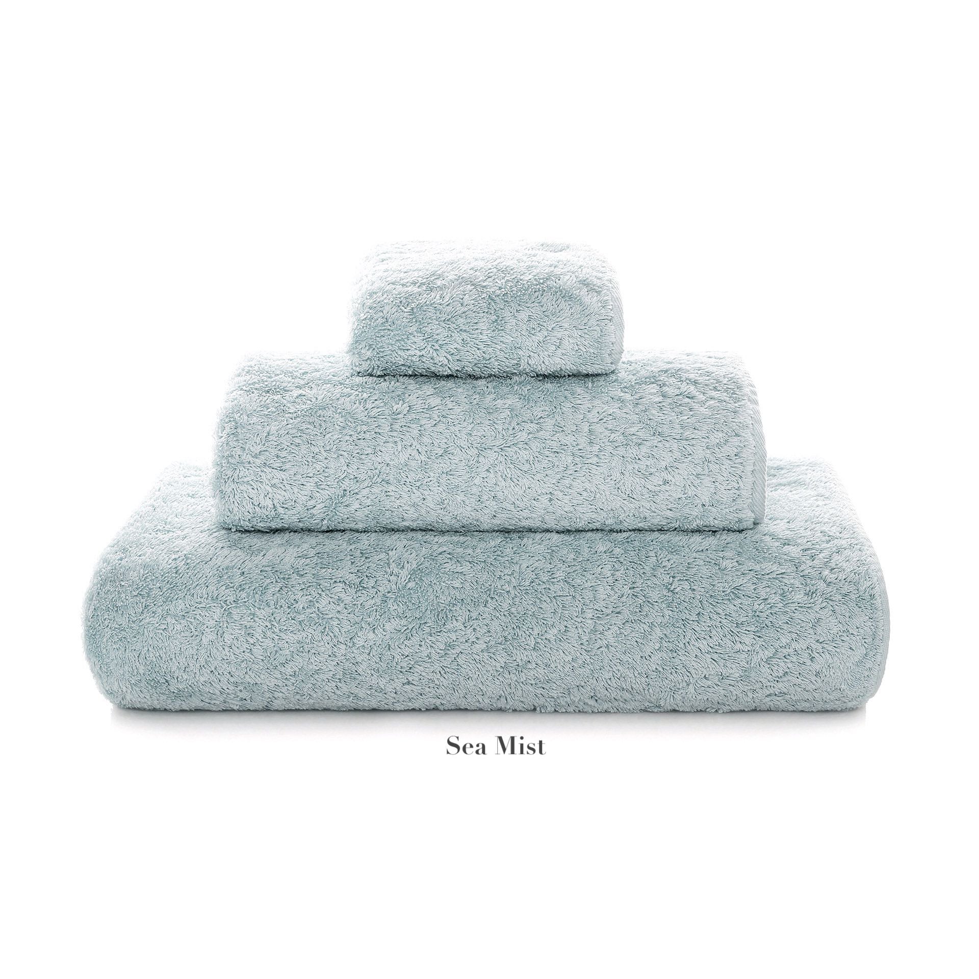 The Graccioza Egoist Bath Collection features three light blue "Sea Mist" Egyptian cotton towels of varying sizes, stacked in a pyramid shape on a white background.