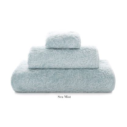 The Graccioza Egoist Bath Collection features three light blue "Sea Mist" Egyptian cotton towels of varying sizes, stacked in a pyramid shape on a white background.