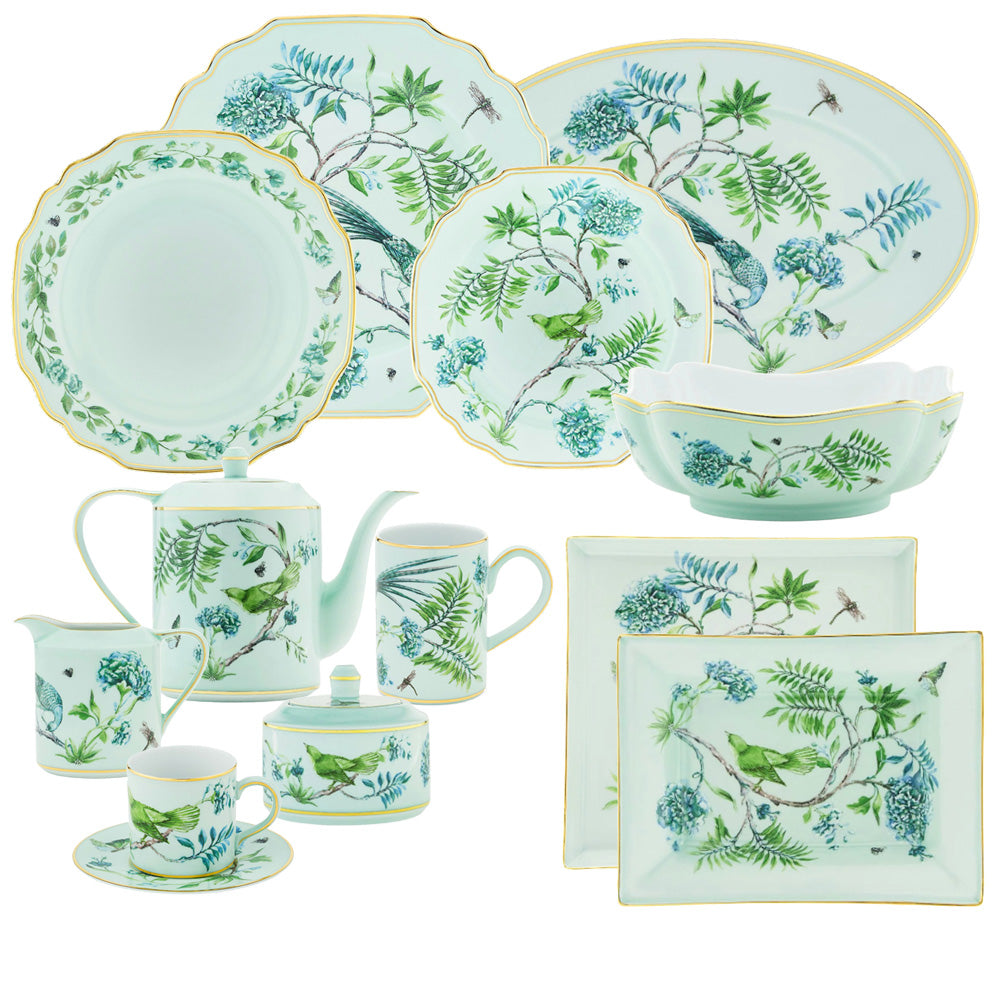 The Aquazzura Casa Secret Garden Dinnerware and Serveware Collection showcases green and blue floral and bird motifs with gold accents on plates, cups, saucers, teapot, sugar bowl, and serving dishes.
