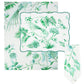 The Aquazzura Casa Secret Garden Table Linen Collection includes a white rectangular tablecloth, placemats, and a folded napkin, all adorned with green botanical and bird illustrations.
