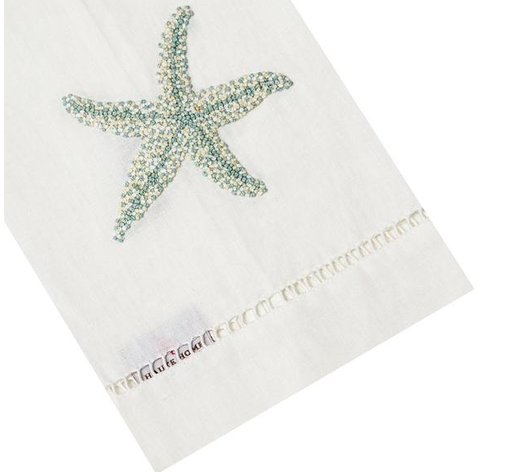 White cloth napkin from the Haute Home Starfish Coaster & Bath Collection, crafted from premium linen with a blue beaded starfish motif and a decorative stitched border, elegantly displayed at an angle—a stylish enhancement to your home décor.