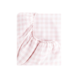 The Gooselings Pink Picnic Gingham Bedding is a folded fitted sheet with a light pink and white check pattern, featuring elastic edges. Made from pure materials and OEKO-TEX certified, it ensures breathable comfort for baby bedding.