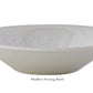 The Jars Vuelta White Pearl Collection features a white, shallow serving bowl with a wide rim and subtle interior texture, finished with a perle glaze. Dishwasher safe for easy cleaning, it's shown against a plain background.